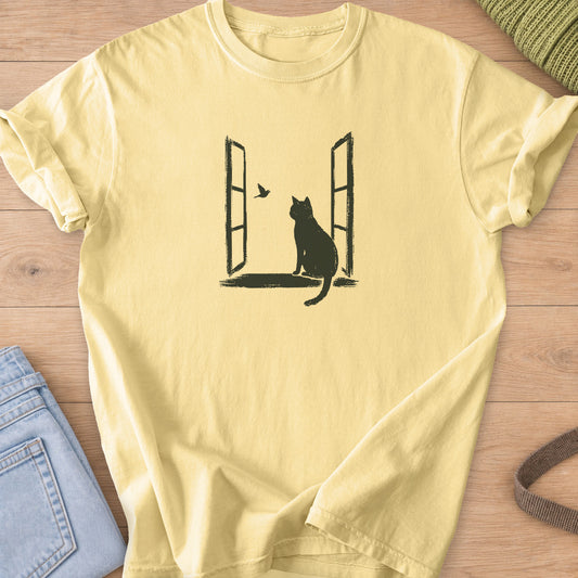 Cat sitting on the sill of an open window, watching a small bird fly past, dark charcoal ink on a Butter T-Shirt