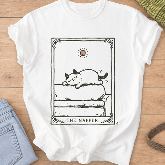 Tarot-style card of a cat napping on a sofa under a small sun, "THE NAPPER.", dark charcoal ink on a White T-Shirt