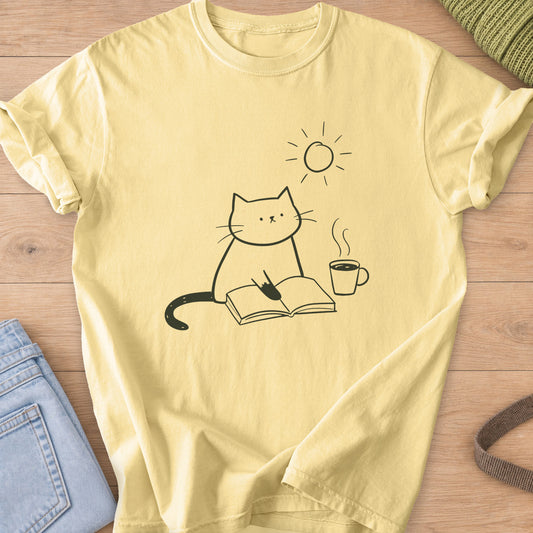 Cat reading an open book beside a steaming coffee mug, with the sun above, dark charcoal ink on a Butter T-Shirt