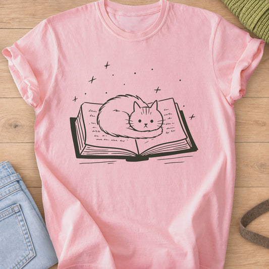 Fluffy cat curled up on an open book with sparkles and stars floating above, dark charcoal ink on a Blossom T-Shirt