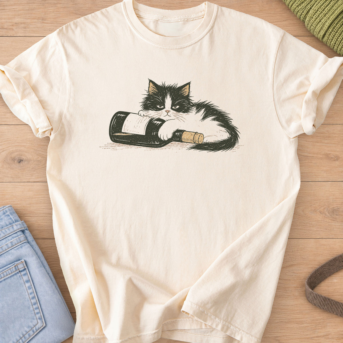 Fluffy black and white cat lying on a tipped-over wine bottle with a cork on an Ivory T-Shirt