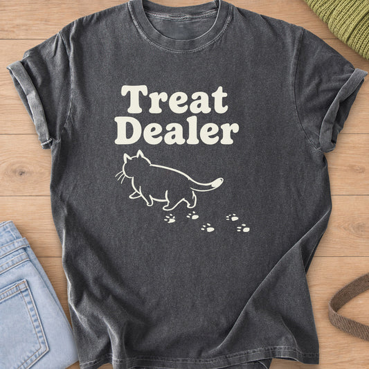 Chubby cat outline walking away under "Treat Dealer" with a trail of paw prints, cream ink on a Pepper T-Shirt