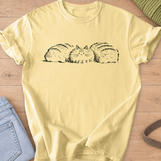 Fluffy cat loaf tucked between two loaves of bread and blending in, dark charcoal ink on a Butter T-Shirt