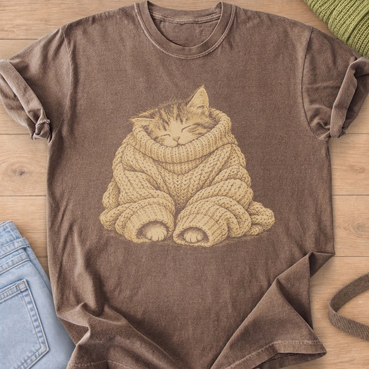 Sleeping tabby kitten bundled in an oversized cable-knit sweater, paws peeking out, tan ink on an Espresso T-Shirt