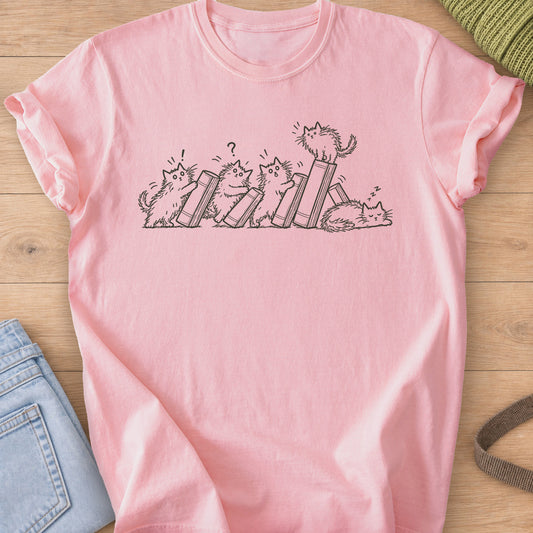 Five fluffy cats toppling books like dominoes, one perched on top, one asleep, dark charcoal ink on a Blossom T-Shirt