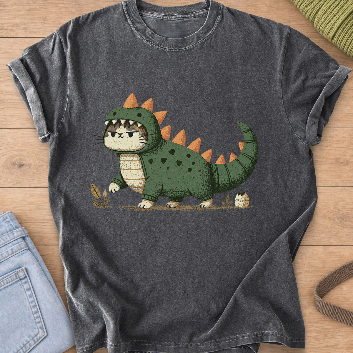 Grumpy cat in a spiky dinosaur costume walking past sprouts and a hatching egg on a Pepper T-Shirt