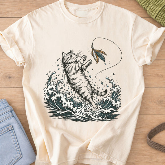 Tabby cat leaping from crashing ocean waves to catch a feather wand toy on an Ivory T-Shirt