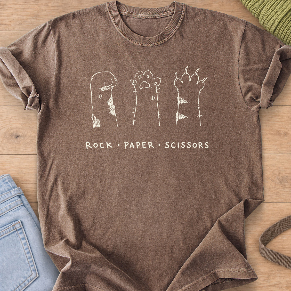Three raised cat paws, curled, open and clawed, above "Rock Paper Scissors", cream ink on an Espresso T-Shirt