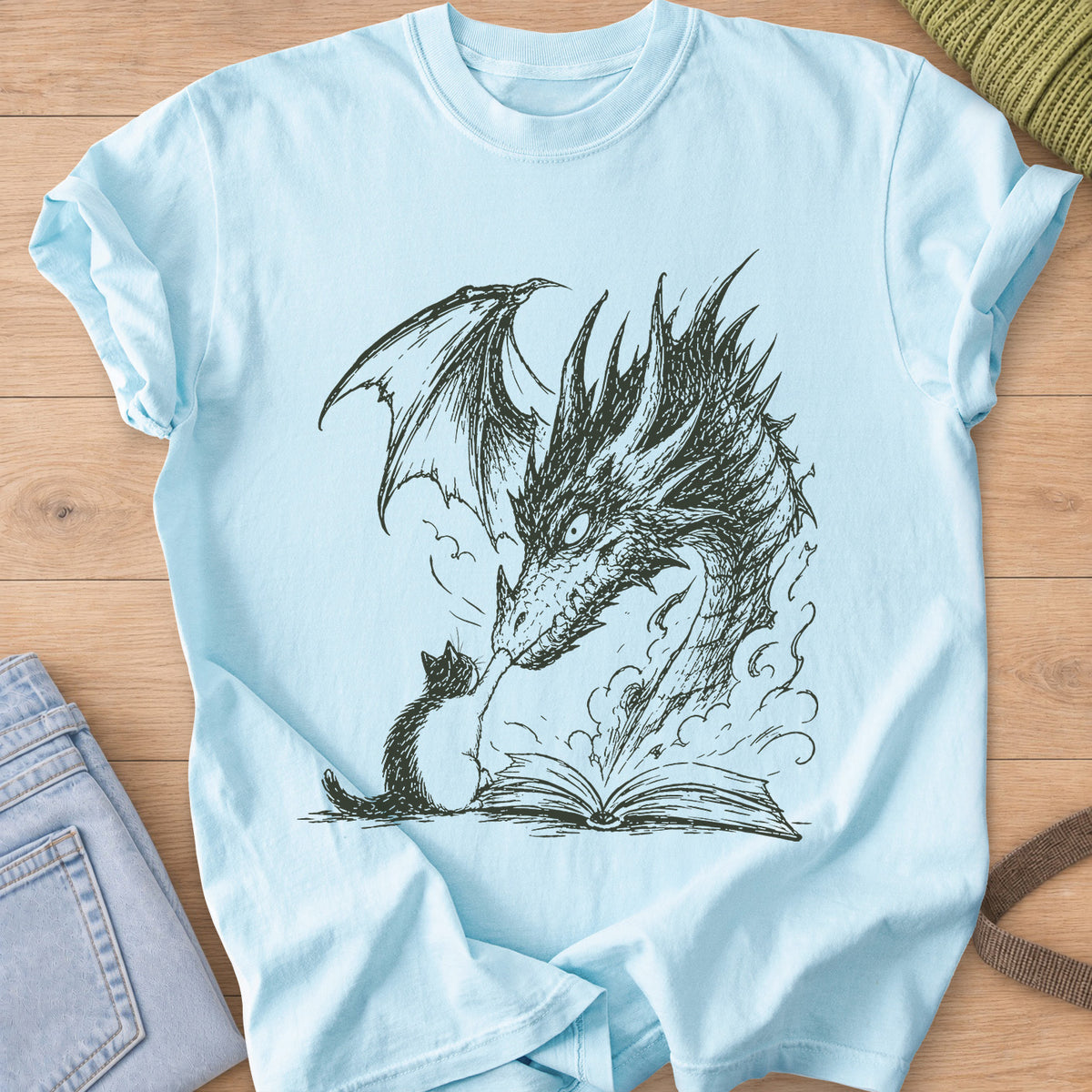 Small cat reaching up to a winged dragon's snout over an open book with smoke, dark charcoal ink on a Chambray T-Shirt