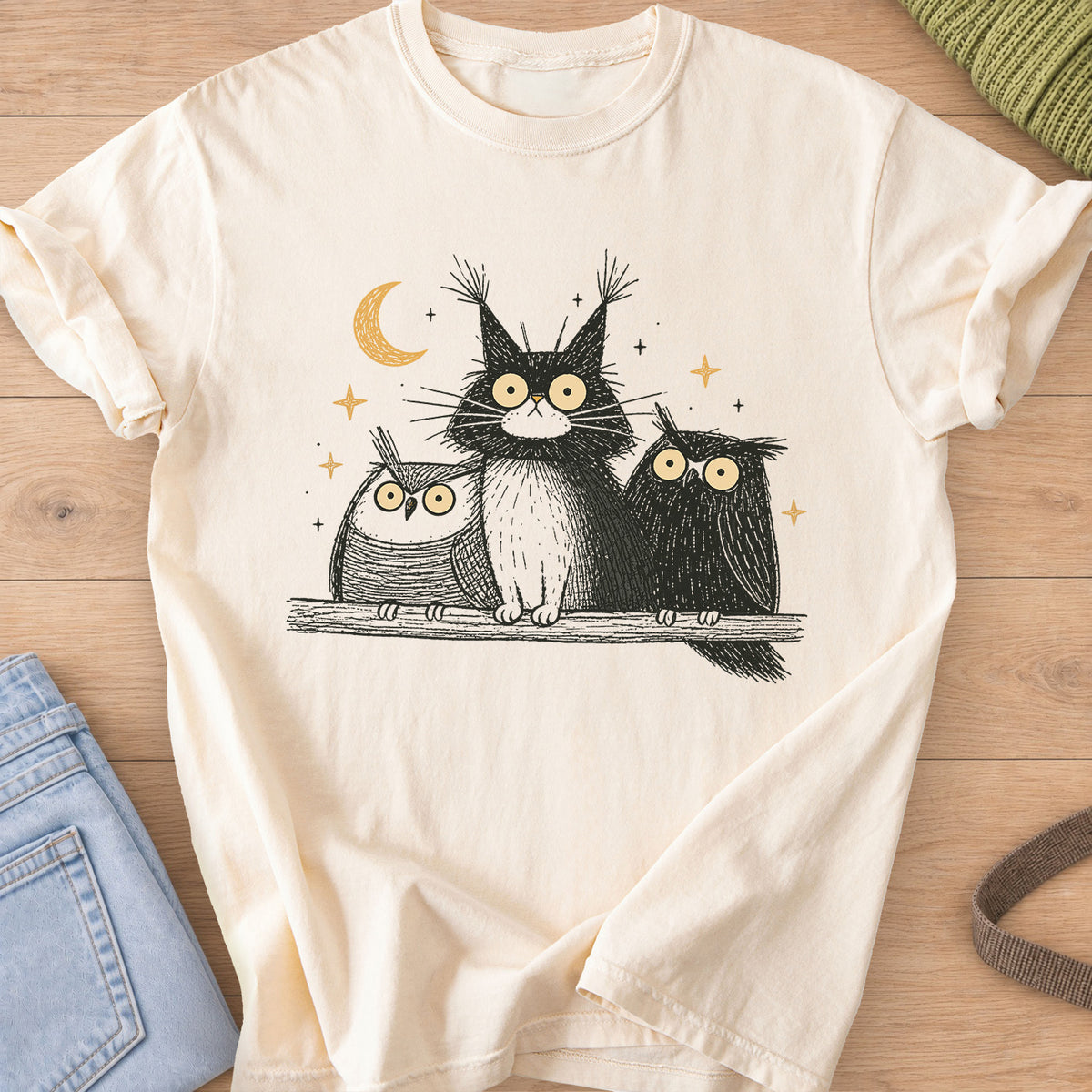 Wide-eyed fluffy cat on a branch between two owls under a crescent moon and stars on an Ivory T-Shirt