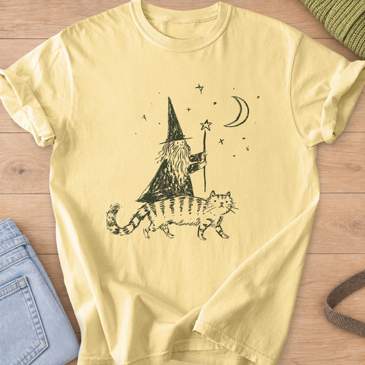 Bearded wizard with a star staff riding a striped cat under a moon and stars, dark charcoal ink on a Butter T-Shirt