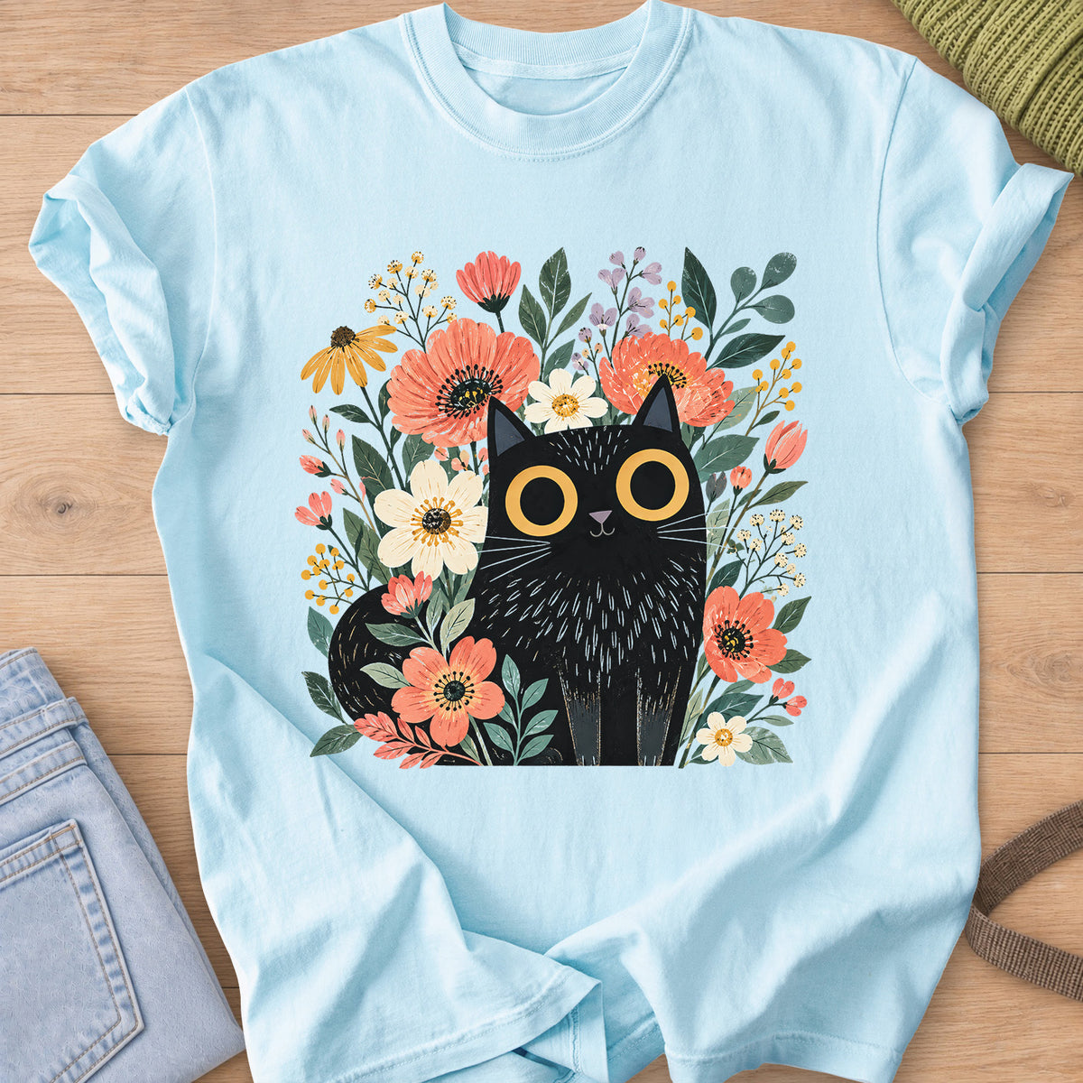 Black cat with big round eyes sitting among wildflowers, daisies and leaves on a Chambray T-Shirt