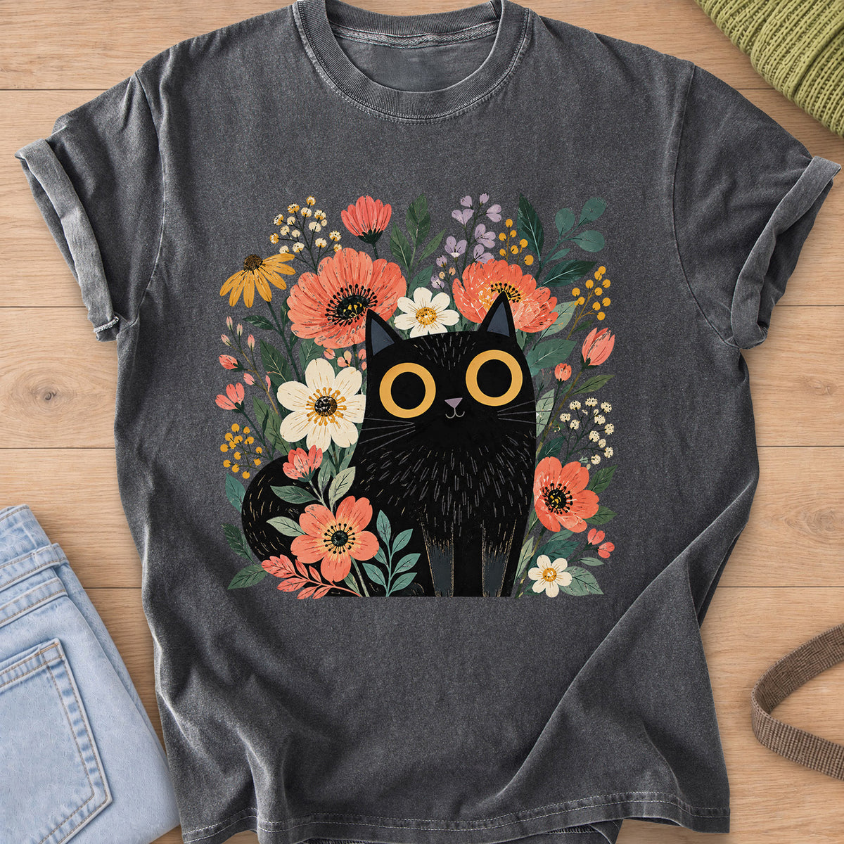 Black cat with big round eyes sitting among wildflowers, daisies and leaves on a Pepper T-Shirt
