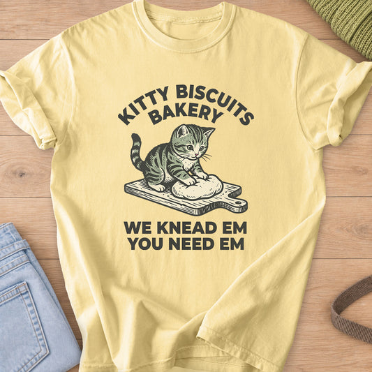 Tabby kitten kneading dough on a cutting board under "Kitty Biscuits Bakery" on a Butter T-Shirt