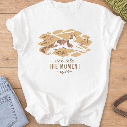 Calico cat stretched out in patches of sunlight with leaves, "sink into the moment" on a White T-Shirt