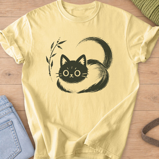 Wide-eyed cat loaf wrapped in a sweeping brushstroke tail beside a bamboo sprig, dark charcoal ink on a Butter T-Shirt