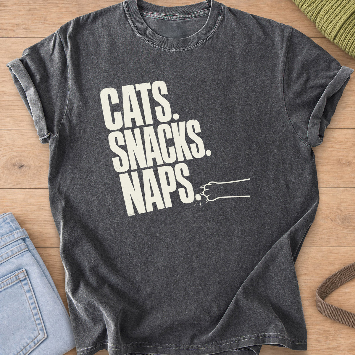 Bold "CATS. SNACKS. NAPS." lettering with a cat paw swatting the last period, cream ink on a Pepper T-Shirt
