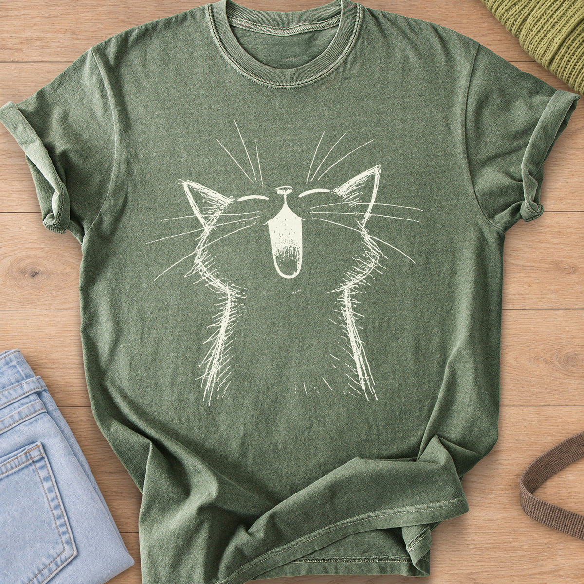 Cat with eyes shut and mouth wide open in a big meow, long whiskers fanning out, cream ink on a Moss T-Shirt