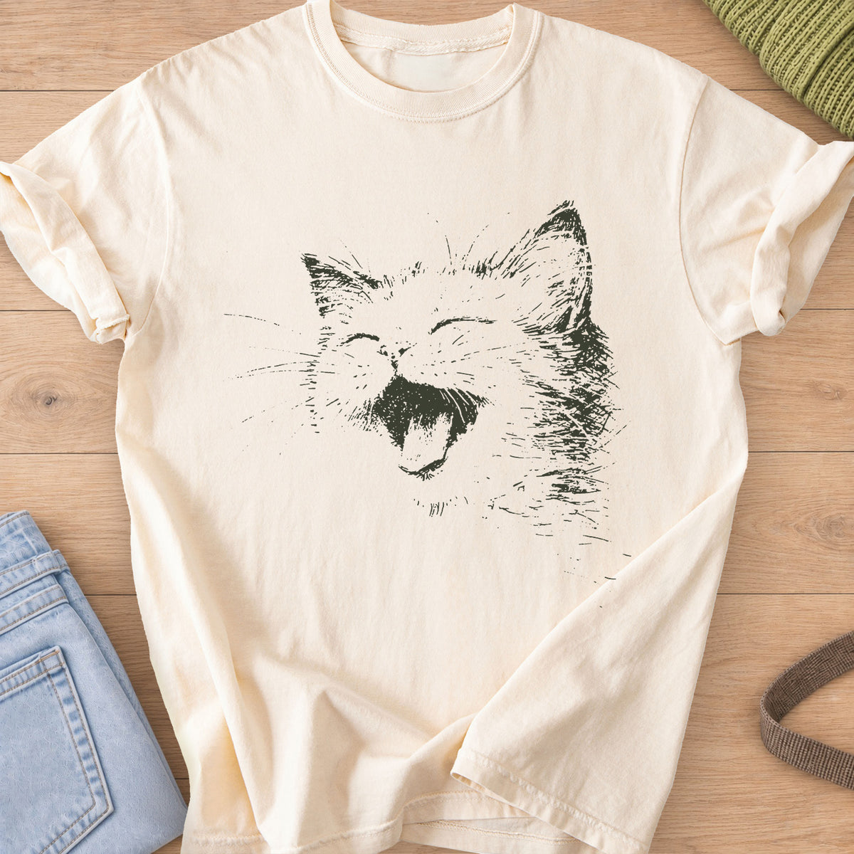 Cat laughing with eyes squeezed shut, mouth wide open and long whiskers, dark charcoal ink on an Ivory T-Shirt