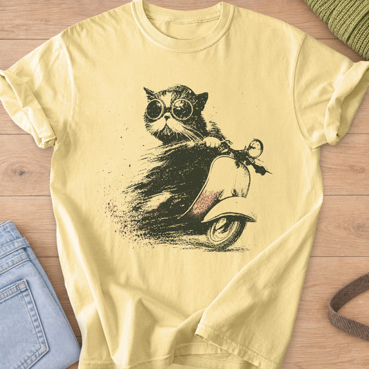 Fluffy cat in round goggles riding a vintage scooter with a dusty speed trail, dark charcoal ink on a Butter T-Shirt