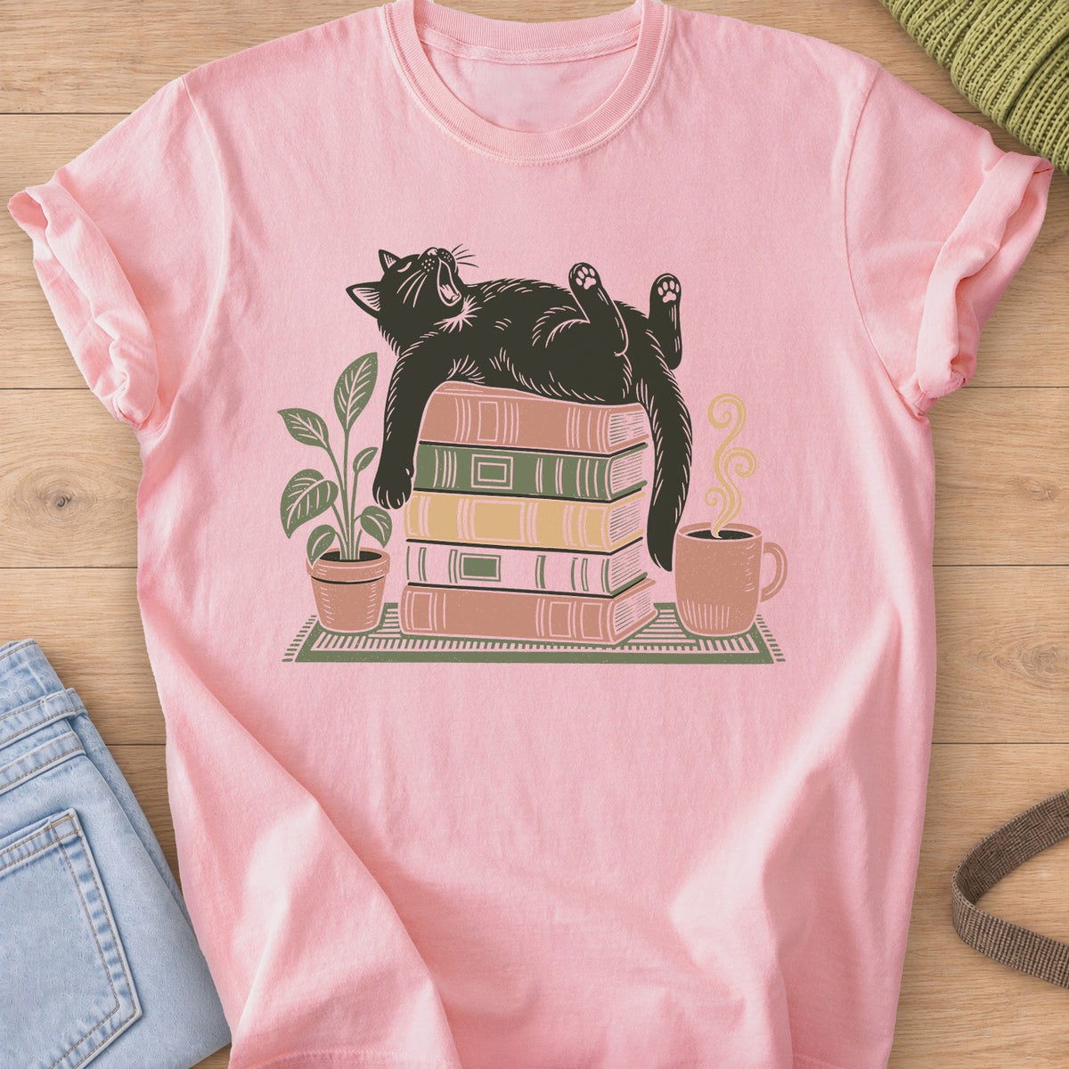 Cat yawning on its back on a stack of books by a potted plant and steaming mug on a Blossom T-Shirt
