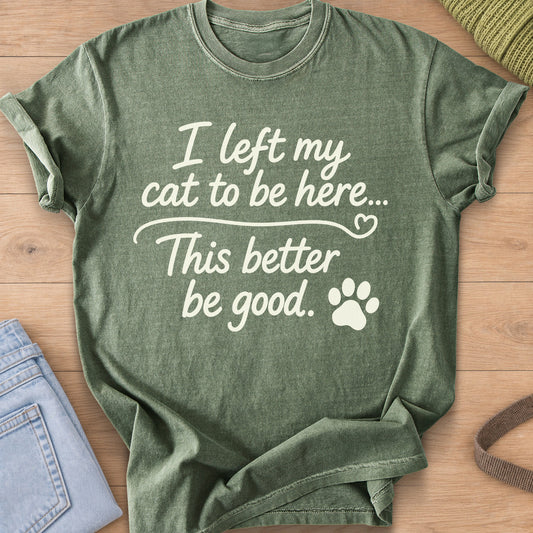 Script text "I left my cat to be here... This better be good." with a paw print, cream ink on a Moss T-Shirt