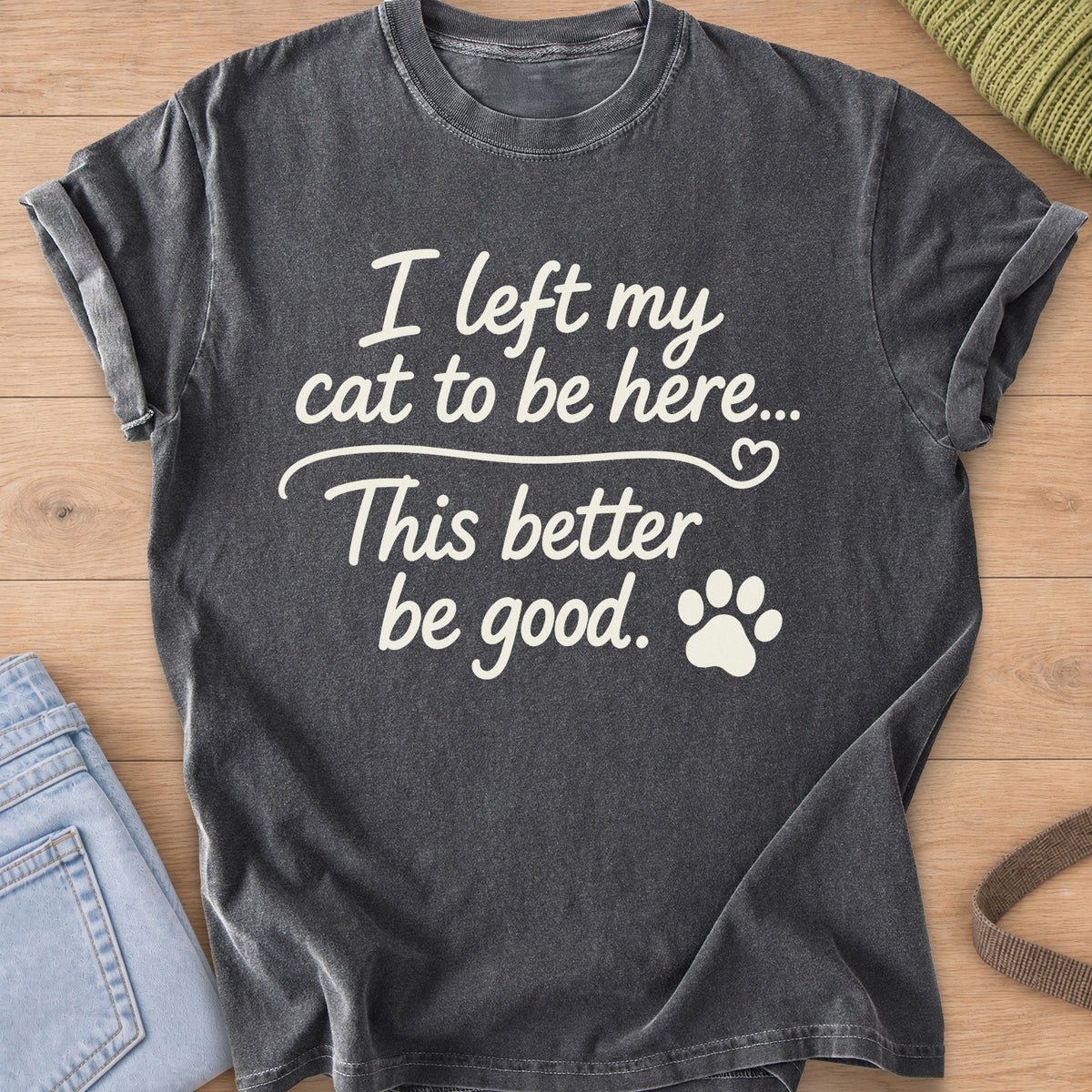 Script text "I left my cat to be here... This better be good." with a paw print, cream ink on a Pepper T-Shirt