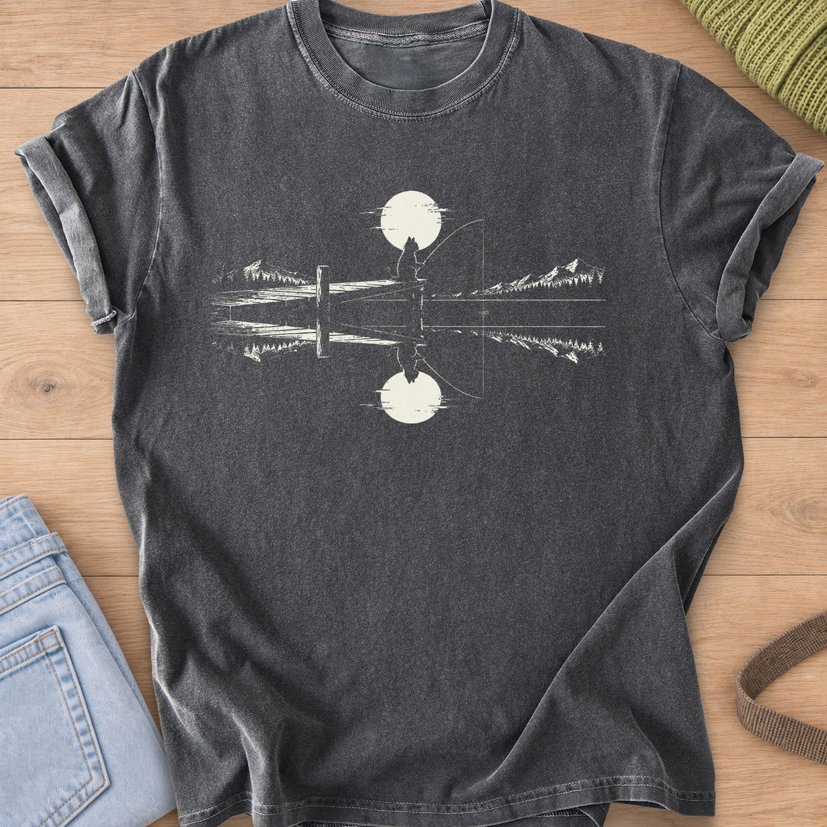 Cat silhouette fishing off a dock under a round sun, mirrored in a mountain lake, cream ink on a Pepper T-Shirt