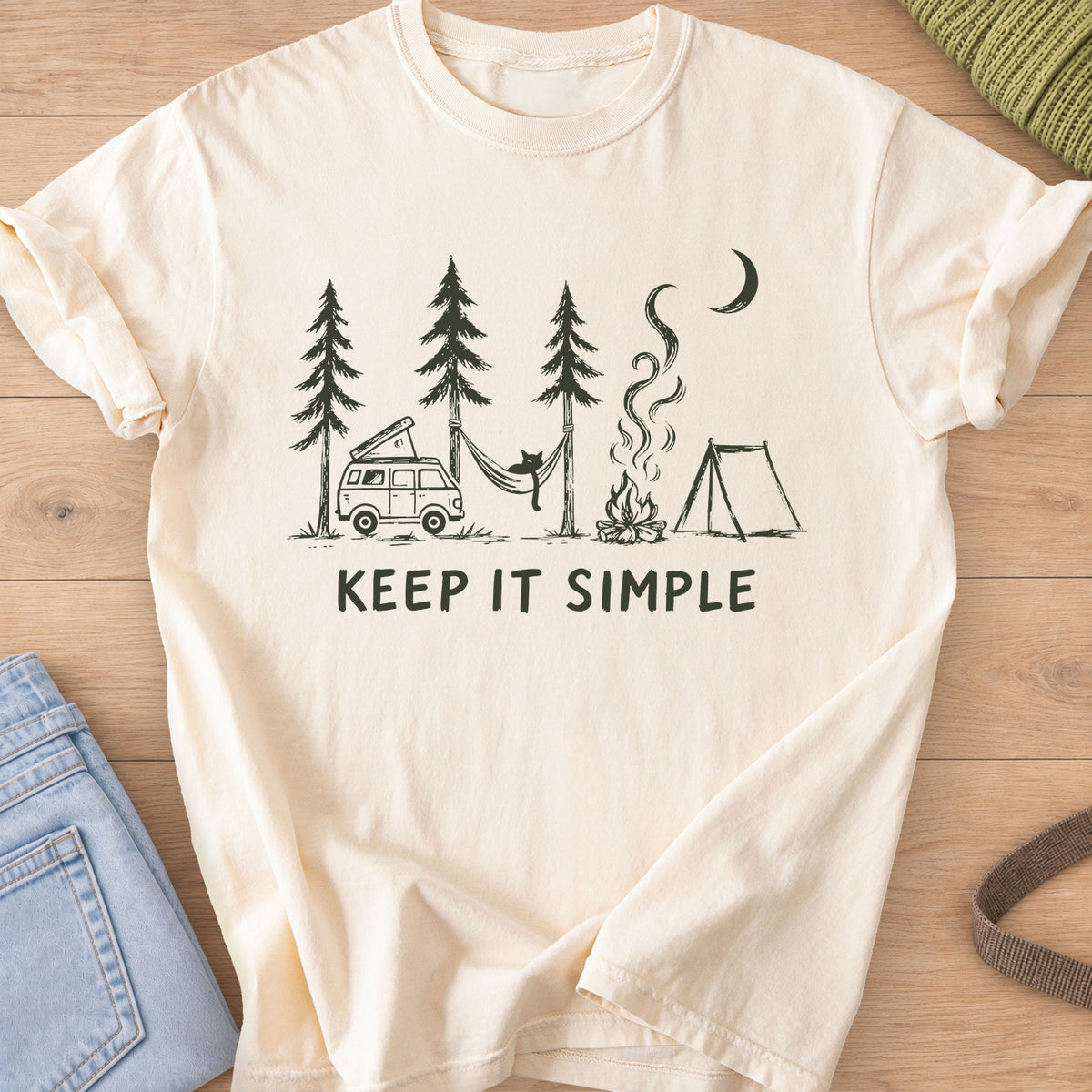 Cat in a hammock between pines with camper van, campfire, tent and "KEEP IT SIMPLE", dark charcoal ink on an Ivory T-Shirt