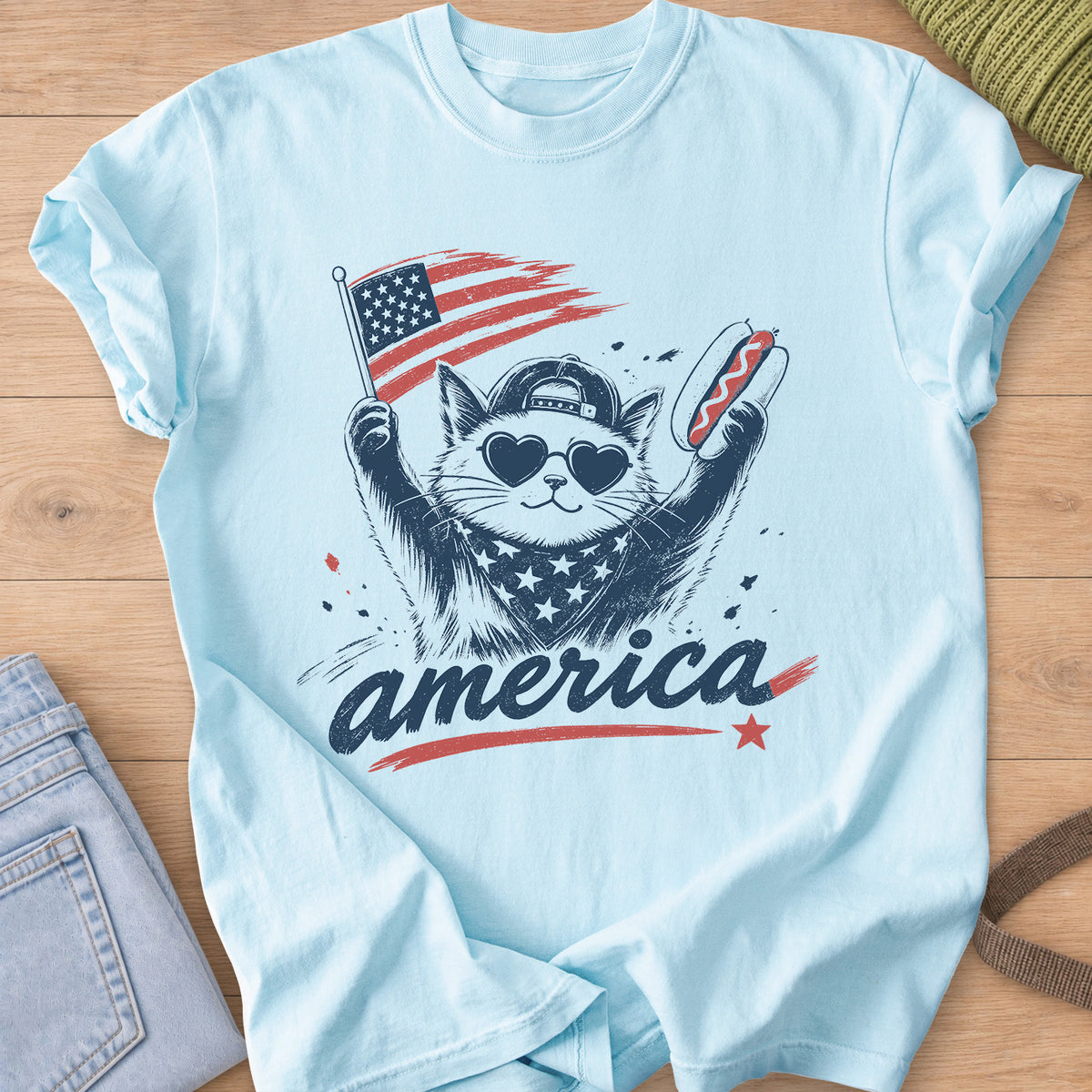Cat in heart sunglasses and a cap holding a flag and a hot dog above "america", navy and red ink on a Chambray T-Shirt