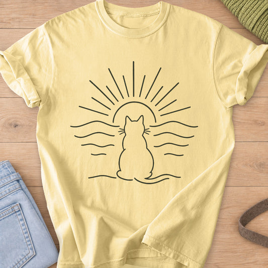 Cat outline seen from behind, watching a setting sun over rippling water, dark charcoal ink on a Butter T-Shirt