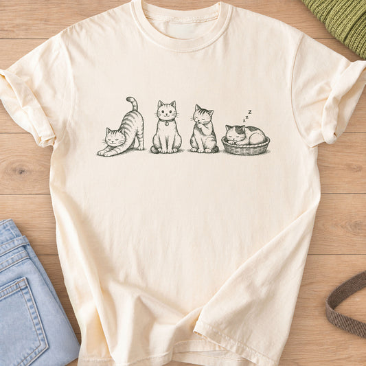 Four tabby cats in a row stretching, sitting, grooming and napping in a basket, dark charcoal ink on an Ivory T-Shirt