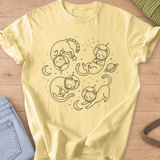 Four cats in astronaut helmets floating among stars, crescent moons and a planet, dark charcoal ink on a Butter T-Shirt