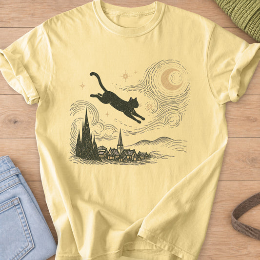 Cat leaps through a swirling night sky with a moon and stars above a village, dark charcoal ink on a Butter T-Shirt