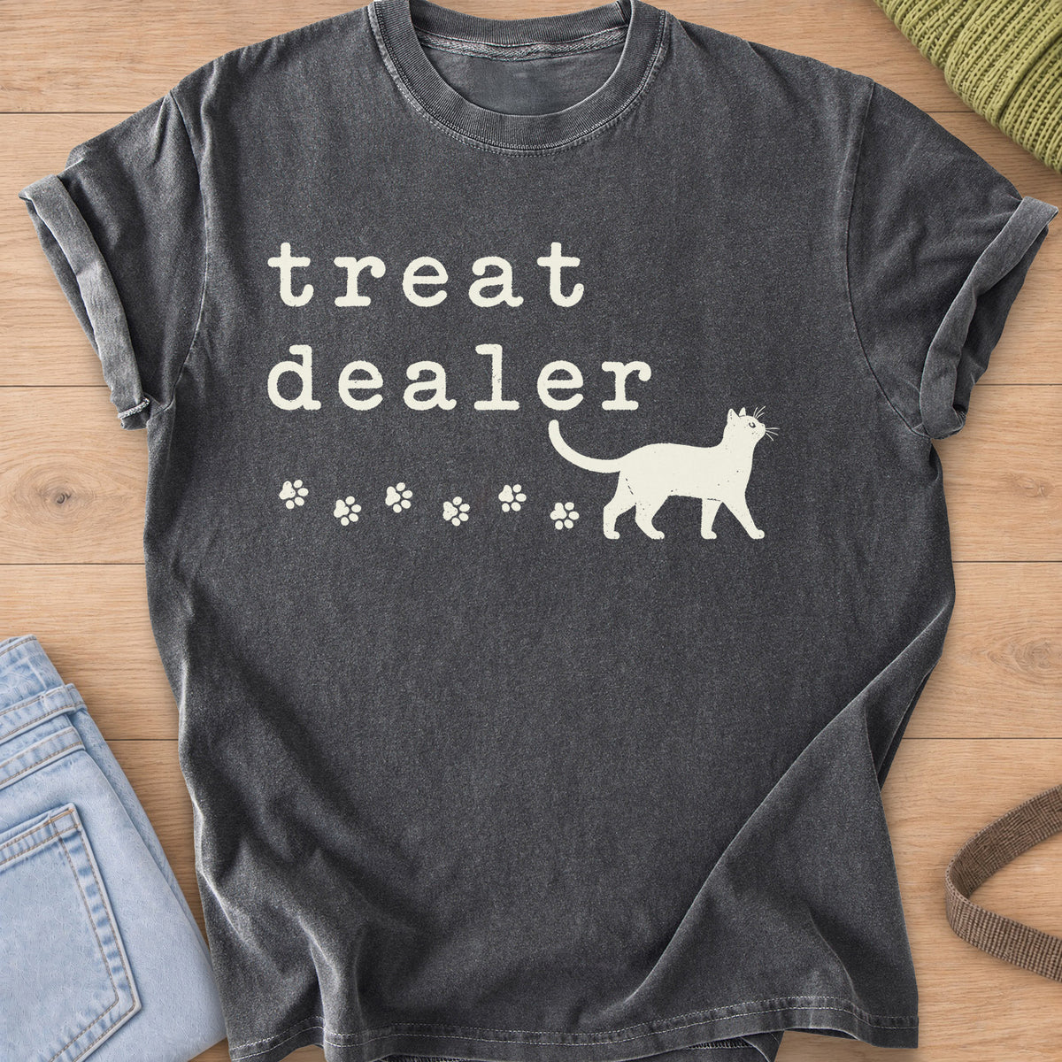 Walking cat silhouette with a trail of paw prints beneath the words "treat dealer", cream ink on a Pepper T-Shirt