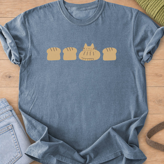 Tabby cat loaf tucked into a row of bread loaves with scored tops, mustard ink on a Blue Jean T-Shirt