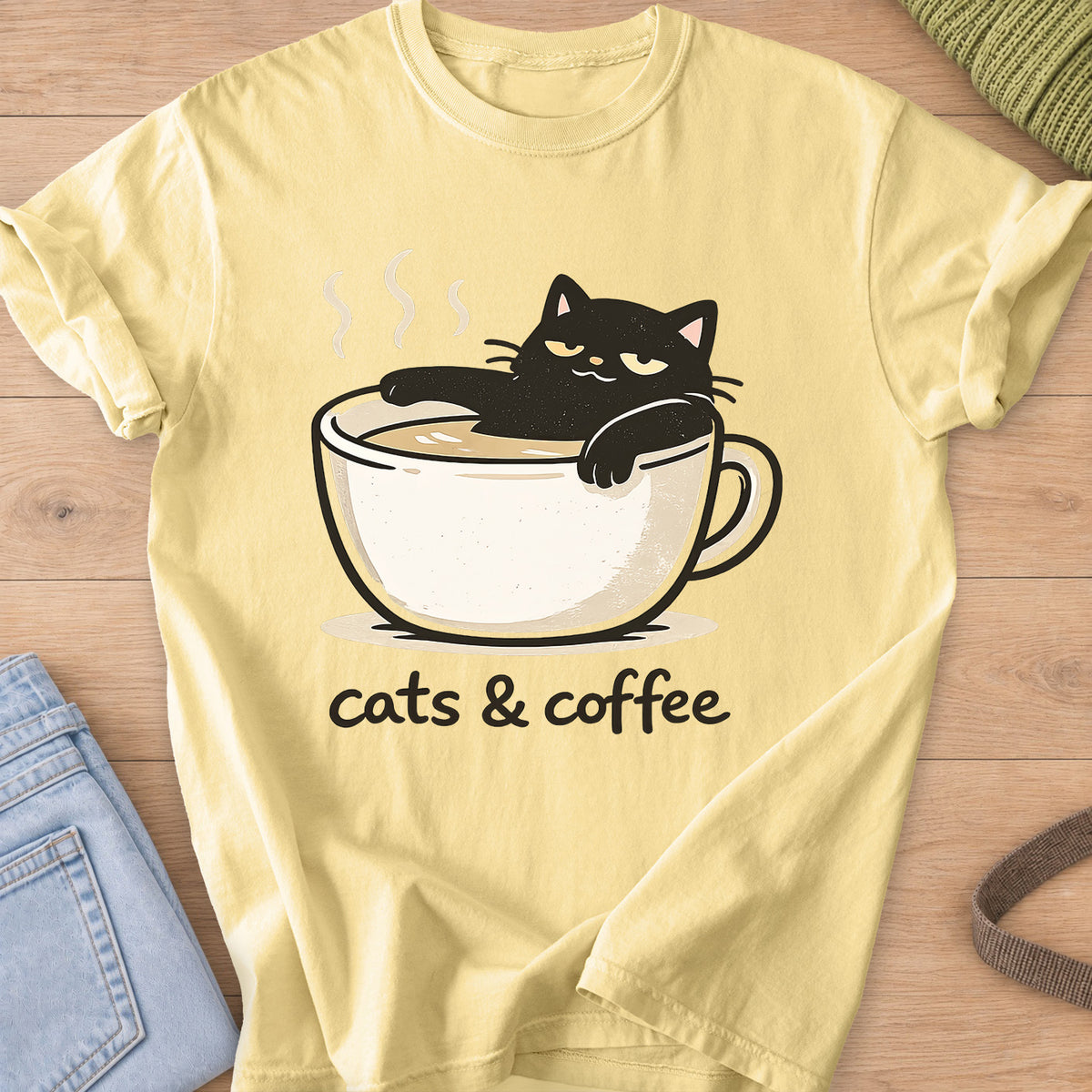 Black cat lounging in a steaming coffee cup above the words "cats & coffee" on a Butter T-Shirt