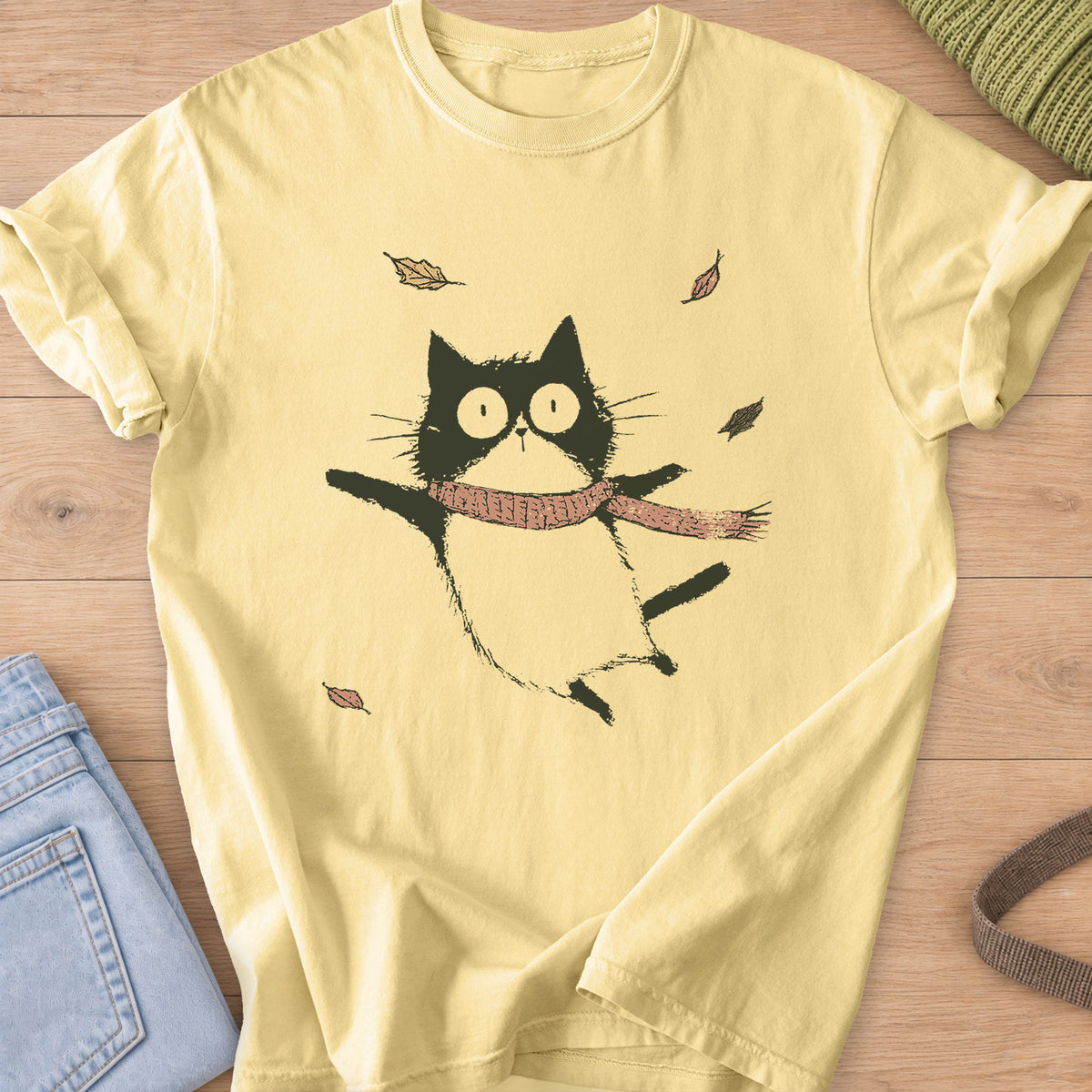 Cat in a knit scarf flying through the air, paws out, among falling autumn leaves on a Butter T-Shirt