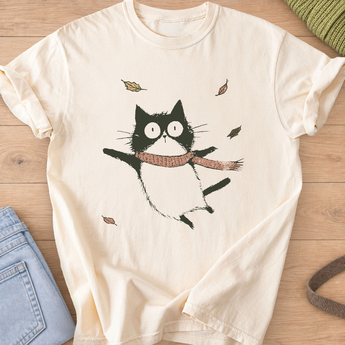 Cat in a knit scarf flying through the air, paws out, among falling autumn leaves on an Ivory T-Shirt