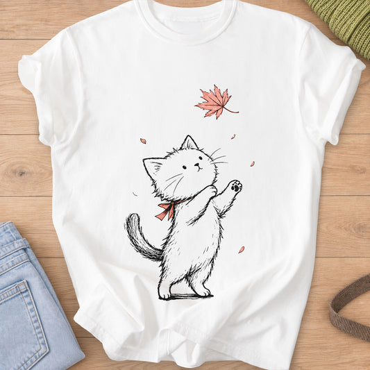 Fluffy cat on hind legs with a neck bow, reaching for a falling maple leaf on a White T-Shirt