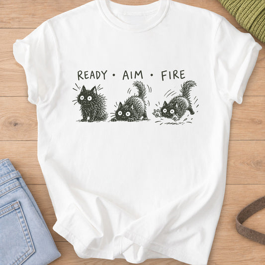 Three wide-eyed fluffy cats sit, crouch and pounce under "Ready Aim Fire", dark charcoal ink on a White T-Shirt