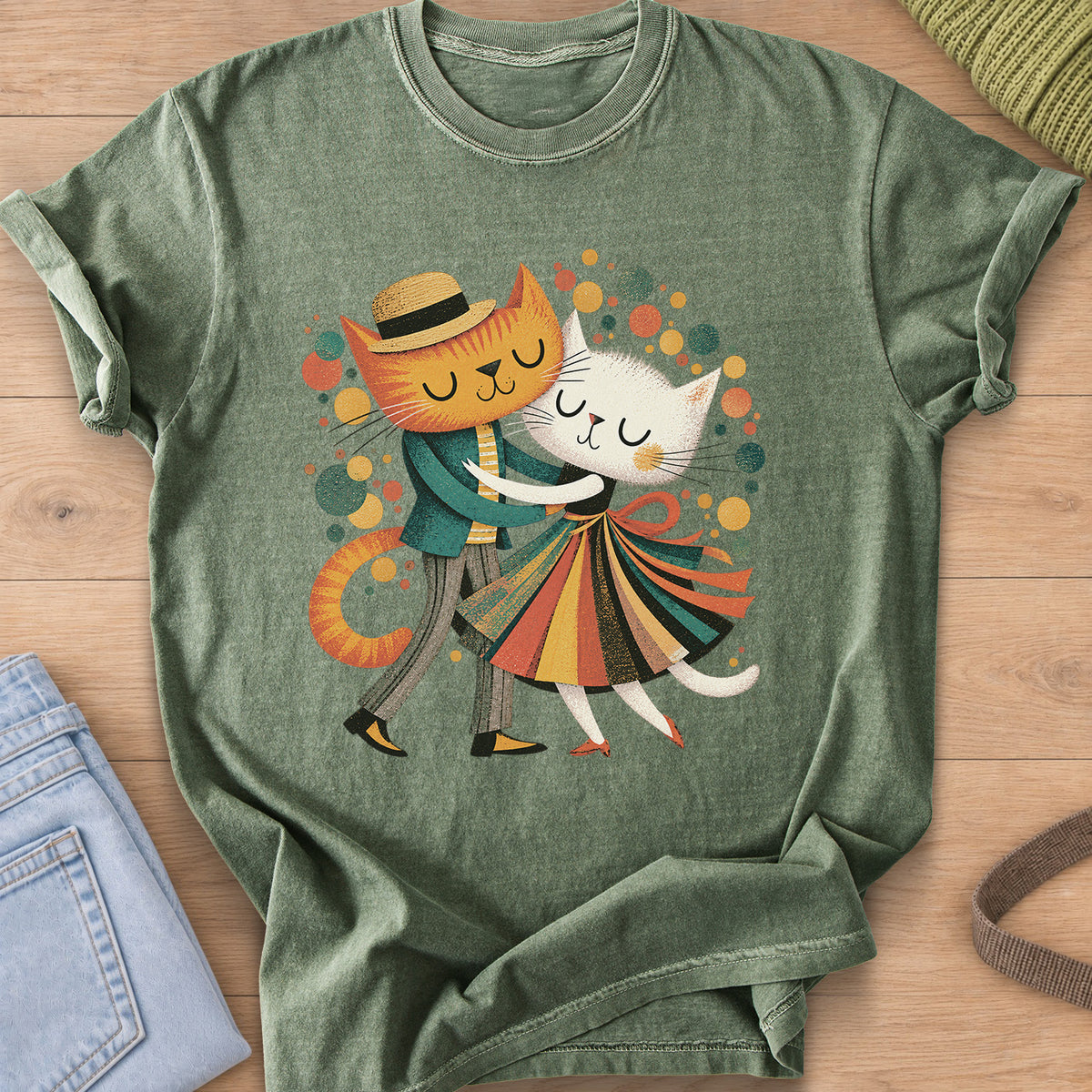 Two cats dance cheek to cheek, one in a straw hat, one in a striped skirt, amid dots on a Moss T-Shirt