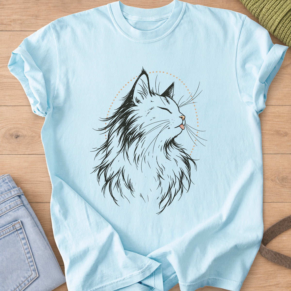 Fluffy cat, eyes closed, tiny tongue out, framed by a dotted arc, black and tan ink on a Chambray T-Shirt