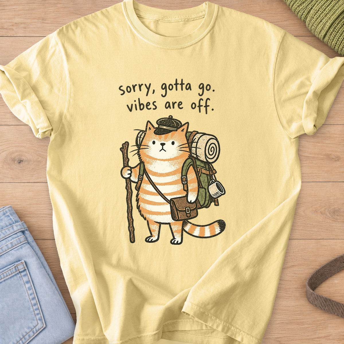 Tabby cat hiker with backpack and walking stick, "sorry, gotta go. vibes are off." on a Butter T-Shirt