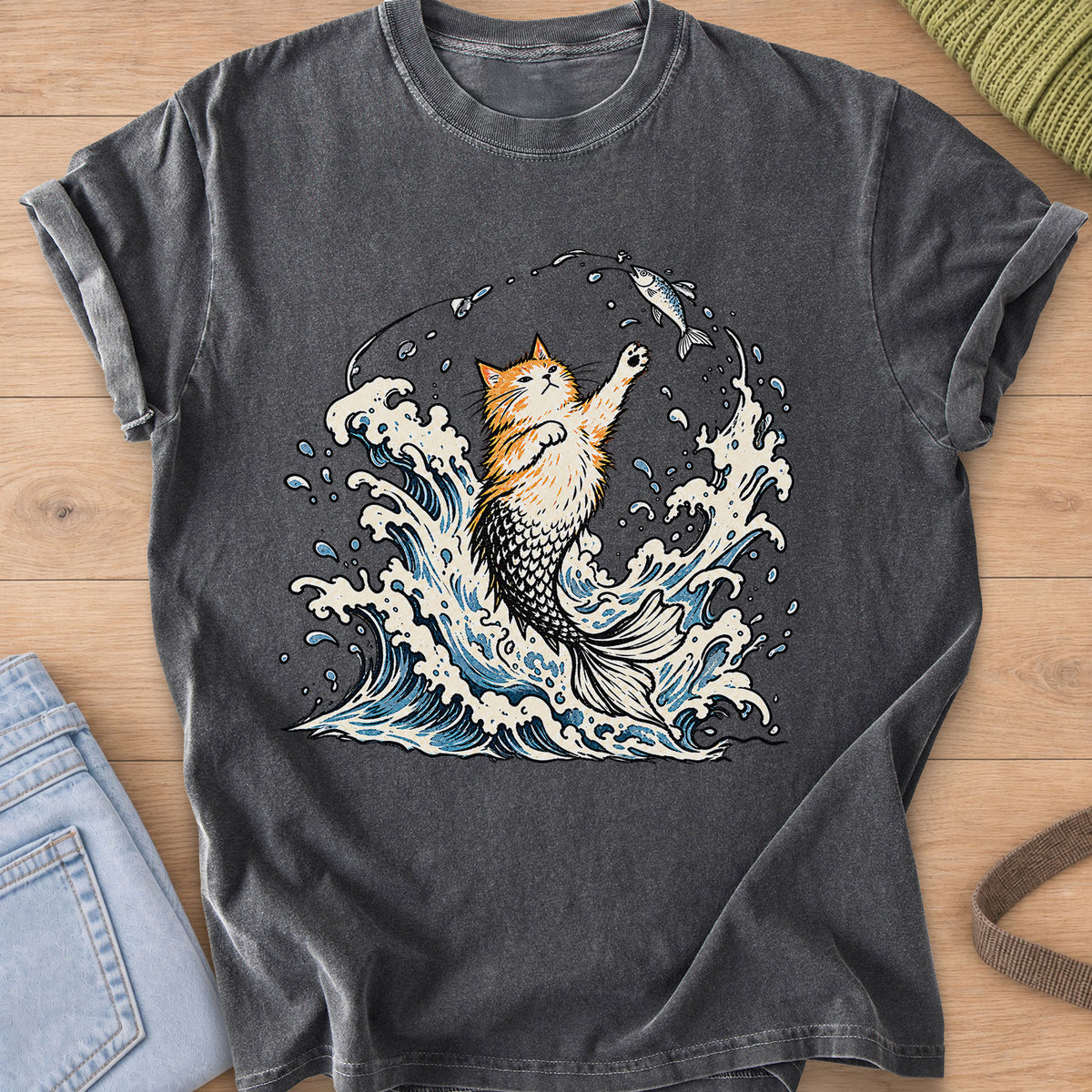 Fluffy cat with a mermaid tail rising from crashing waves, pawing at a hooked fish on a Pepper T-Shirt
