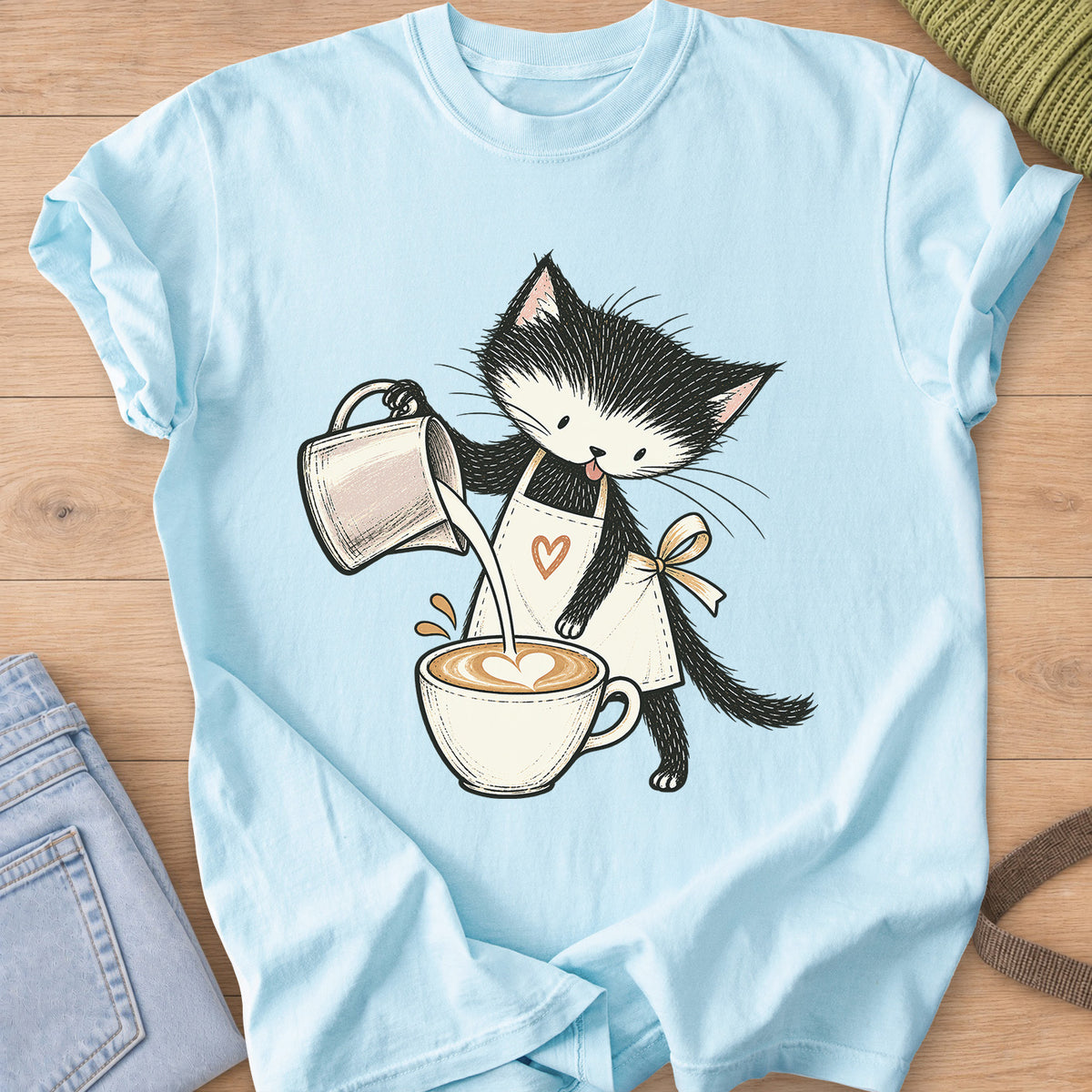 Black and white kitten in an apron pouring milk into a latte with a foam heart on a Chambray T-Shirt