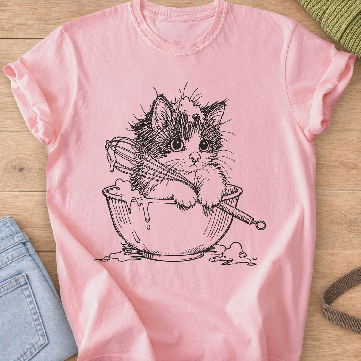 Fluffy kitten in a mixing bowl holding a whisk, with batter dripping over the side, black ink on a Blossom T-Shirt