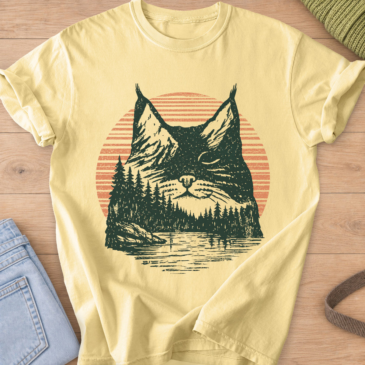 Cat face with closed eyes filled with mountains, pines, a lake and sun, dark green and coral ink on a Butter T-Shirt