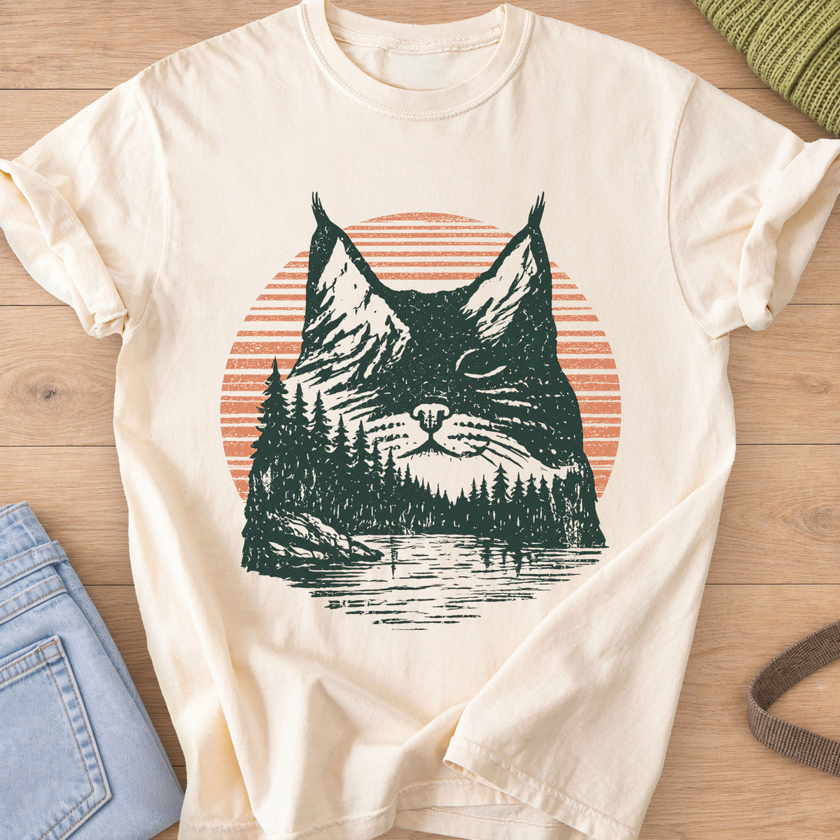 Cat face with closed eyes filled with mountains, pines, a lake and sun, dark green and coral ink on an Ivory T-Shirt