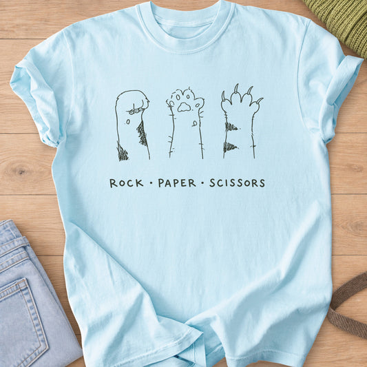 Three raised cat paws, curled, open and clawed, above "Rock Paper Scissors", dark charcoal ink on a Chambray T-Shirt
